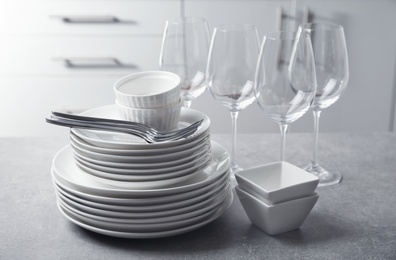 Set of clean dishes and cutlery on table in kitchen