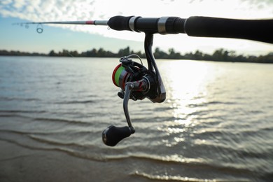Fishing rod with reel near river, closeup