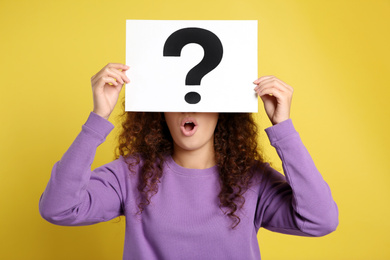 Photo of African-American woman with question mark sign on yellow background