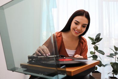 Happy young woman using turntable at home