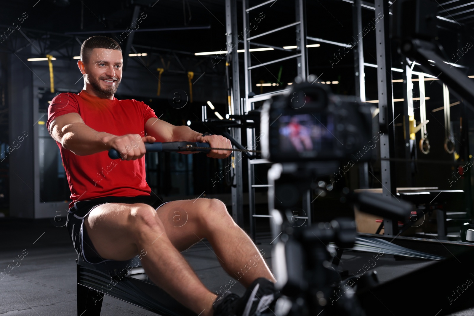 Photo of Man recording workout on camera at gym. Online fitness trainer