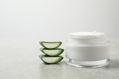 Open jar of cream and cut aloe on grey table. Organic cosmetics