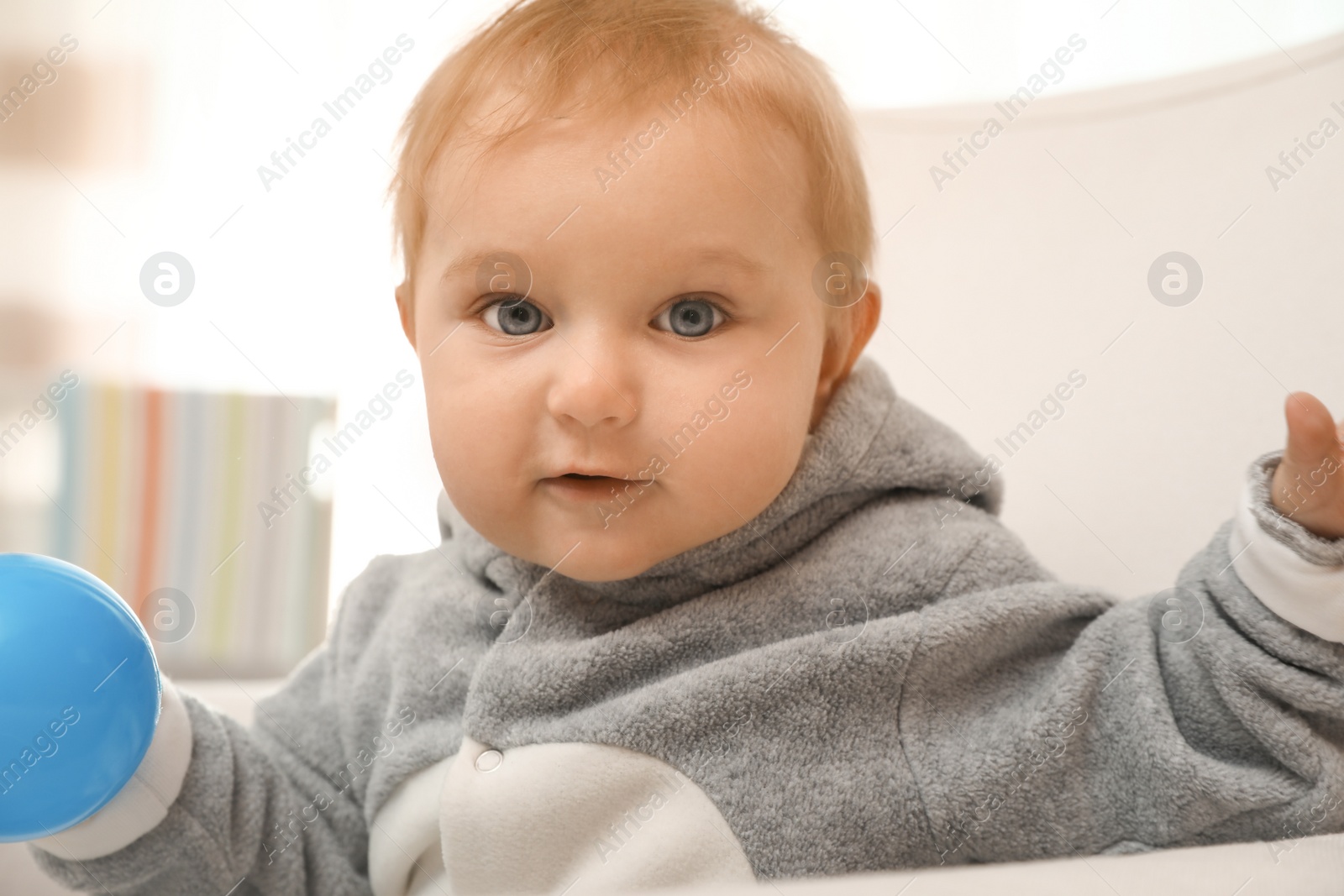 Photo of Cute little baby with blue ball in armchair