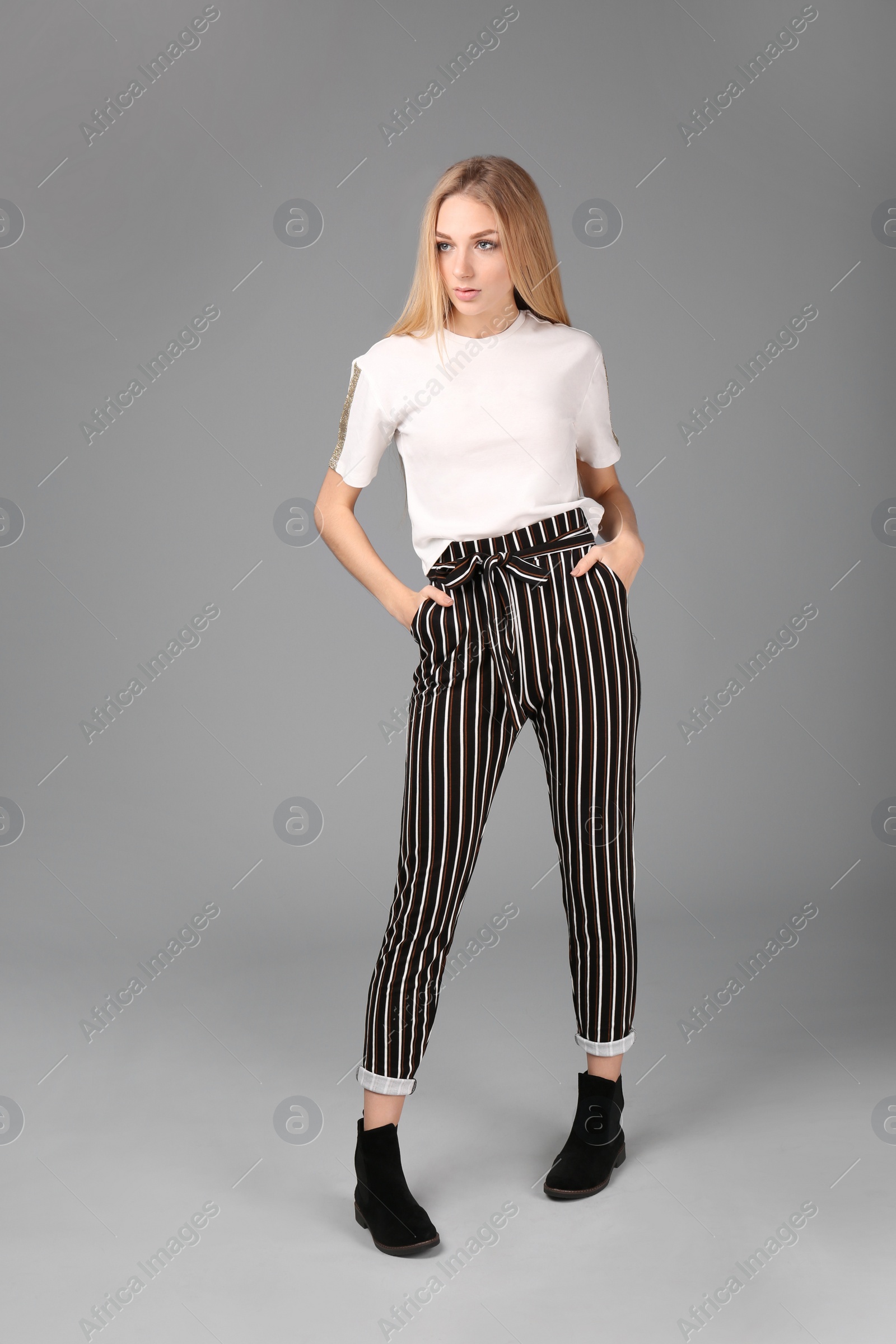 Photo of Young stylish woman in trendy shoes on grey background