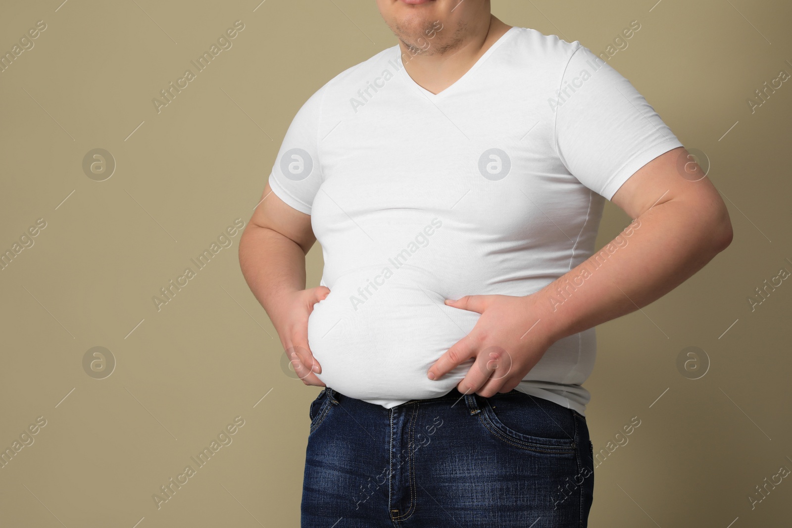 Photo of Overweight man in tight t-shirt on beige background, closeup. Space for text