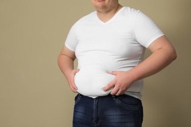 Photo of Overweight man in tight t-shirt on beige background, closeup. Space for text
