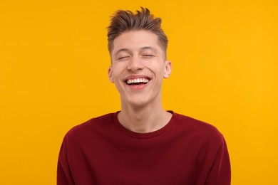 Portrait of young man laughing on orange background