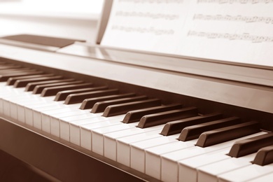 Photo of Modern piano with music sheets in room, closeup