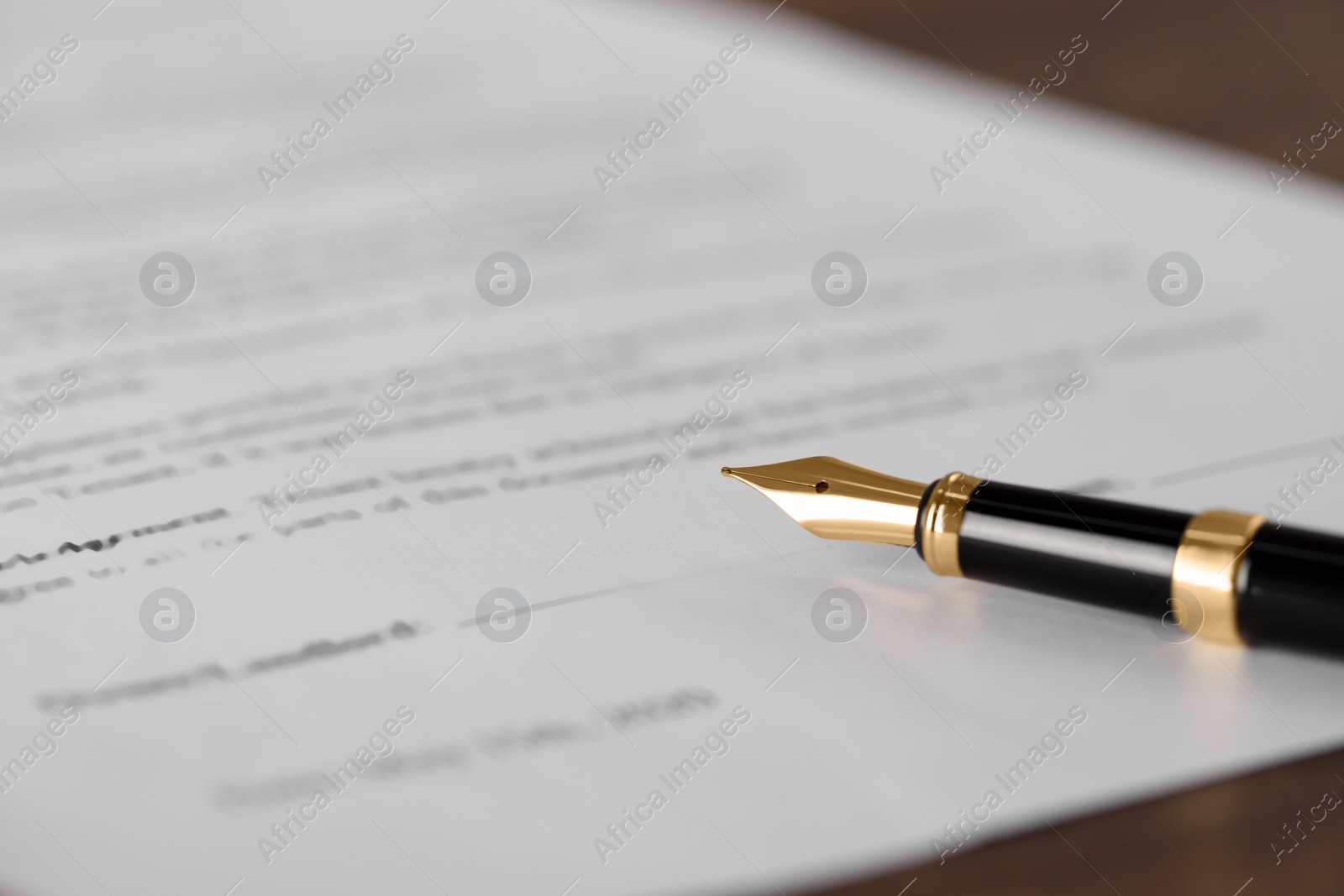 Photo of Fountain pen and document with place for signature on wooden table, closeup and space for text. Notary contract