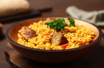 Photo of Plate with rice pilaf and meat on wooden table