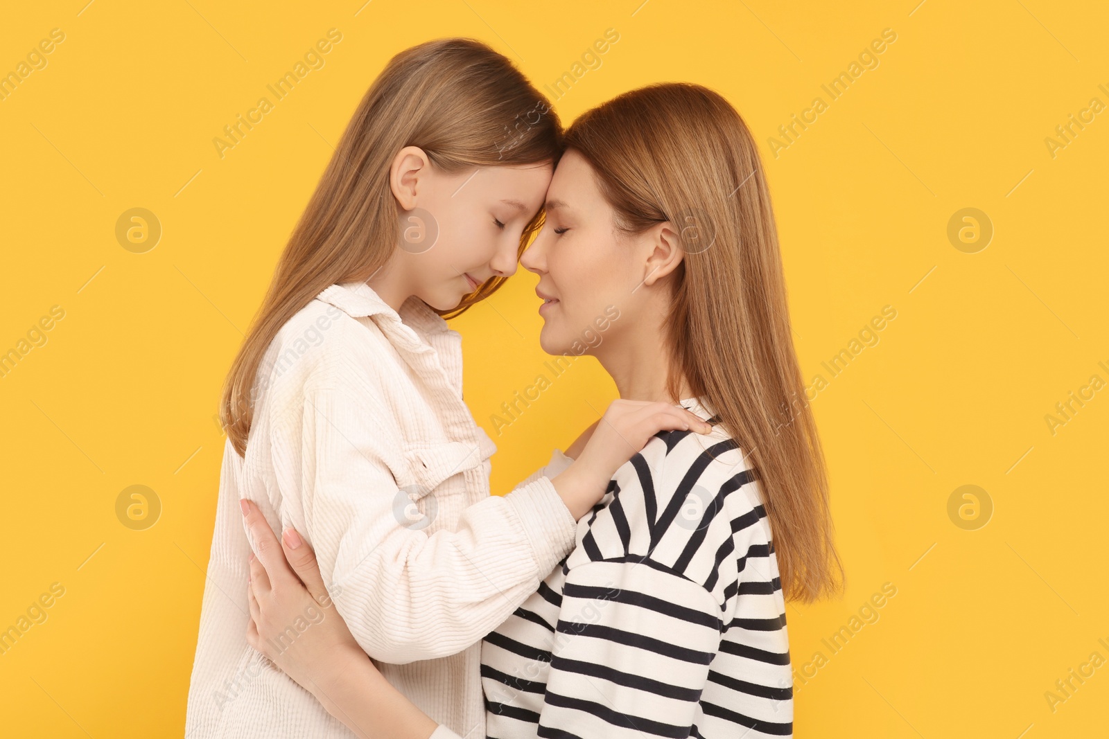 Photo of Portrait of mother and her cute daughter on orange background