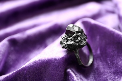Photo of Beautiful silver ring with pyrite gemstones on violet fabric. Space for text