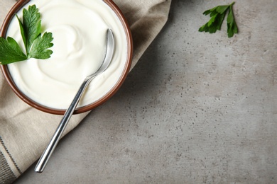 Flat lay composition with sour cream and parsley on grey table, space for text