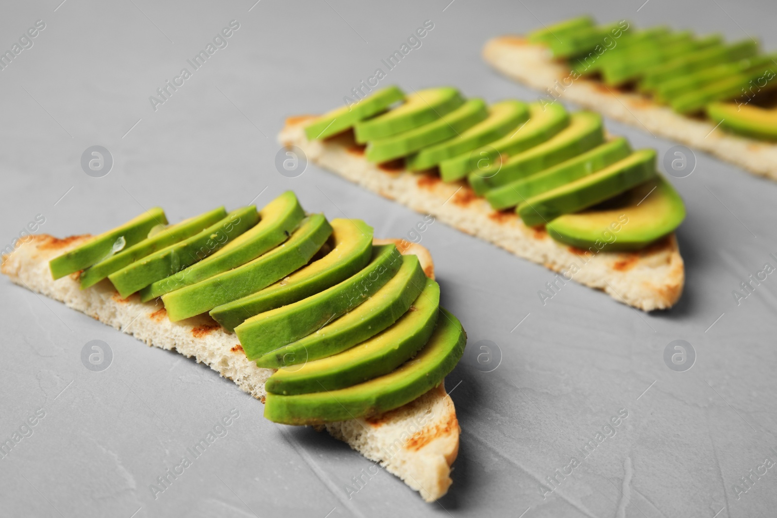 Photo of Tasty toasts with avocado on light grey table, closeup