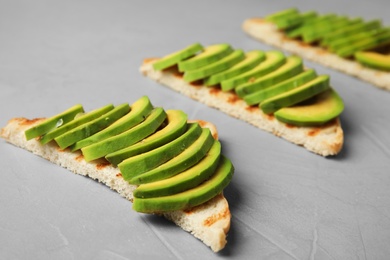 Photo of Tasty toasts with avocado on light grey table, closeup