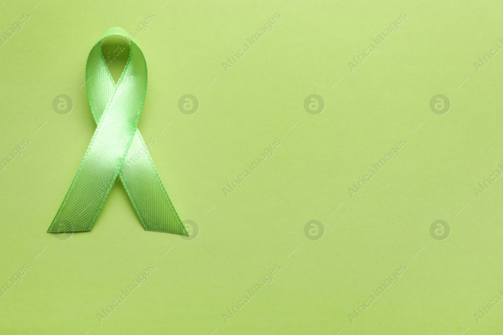 Photo of World Mental Health Day. Green ribbon on color background, top view with space for text