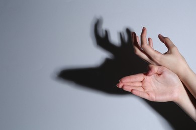 Shadow puppet. Woman making hand gesture like deer on grey background, closeup. Space for text