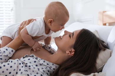 Photo of Mother with her cute baby on bed at home