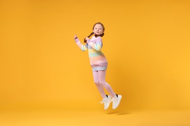 Cute little girl dancing on orange background