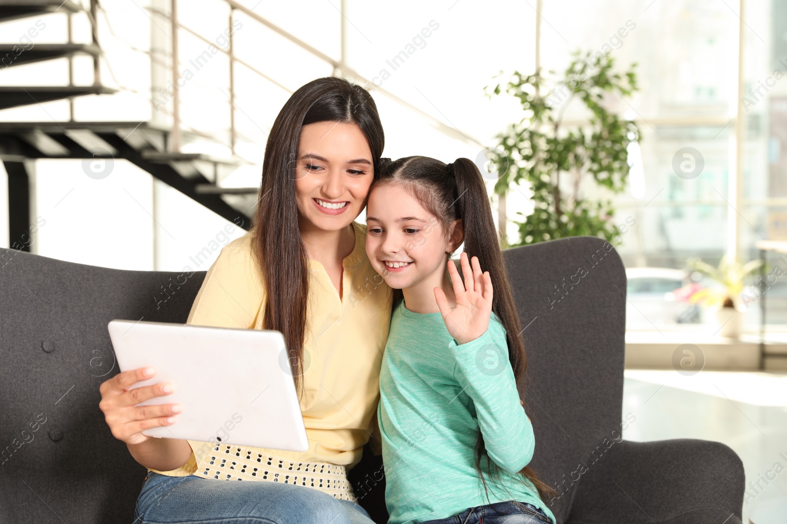 Photo of Mother and daughter using video chat on tablet at home