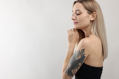 Photo of Portrait of beautiful tattooed woman on light background, space for text