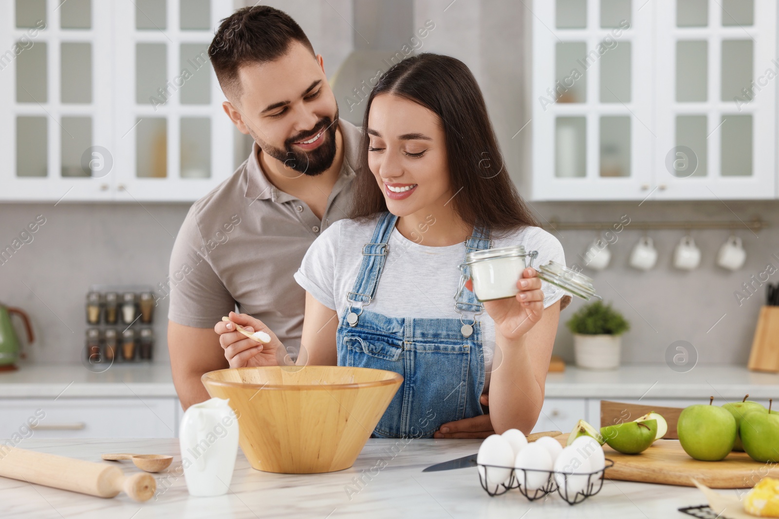 Photo of Happy young couple cooking together in kitchen