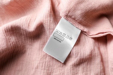 Photo of Clothing label on beautiful pink garment, closeup