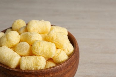 Photo of Bowl of corn sticks on wooden table, closeup. Space for text