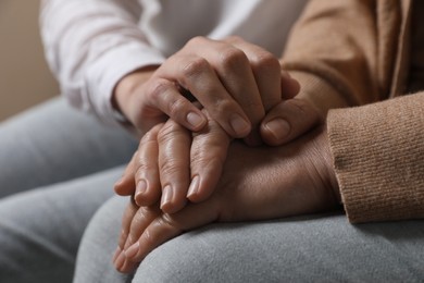 Photo of Woman holding hands with her mother, closeup