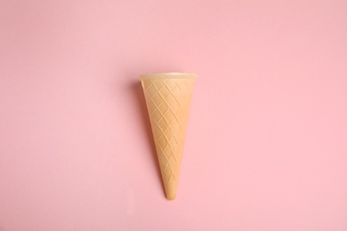 Empty wafer ice cream cone on pink background, top view