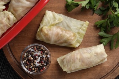 Photo of Uncooked stuffed cabbage rolls on wooden board, flat lay