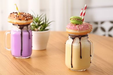 Photo of Mason jars with delicious milk shakes on table