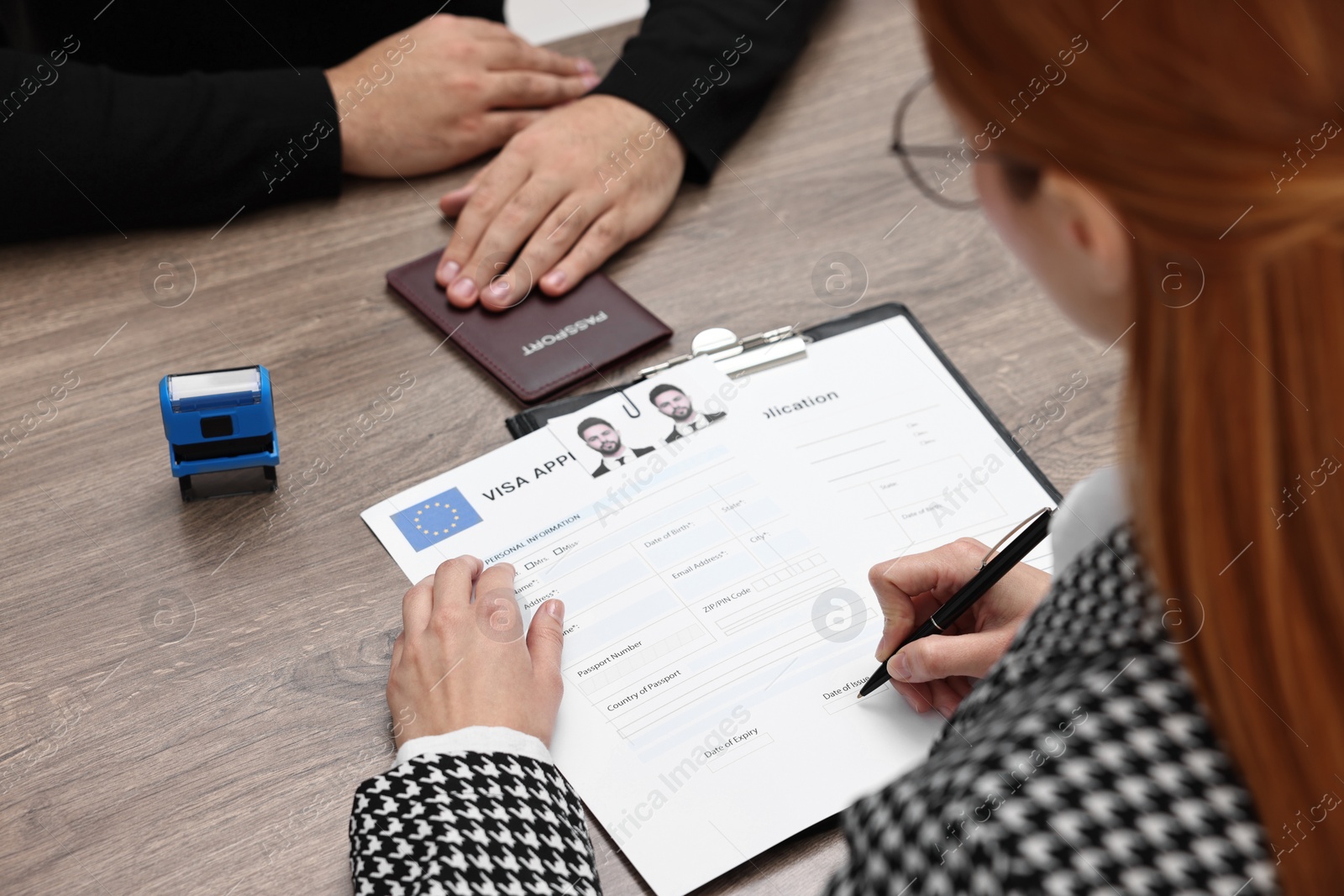 Photo of Immigration to European Union. Embassy worker signing visa application form at wooden table, closeup