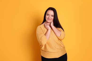 Beautiful overweight woman with charming smile on yellow background