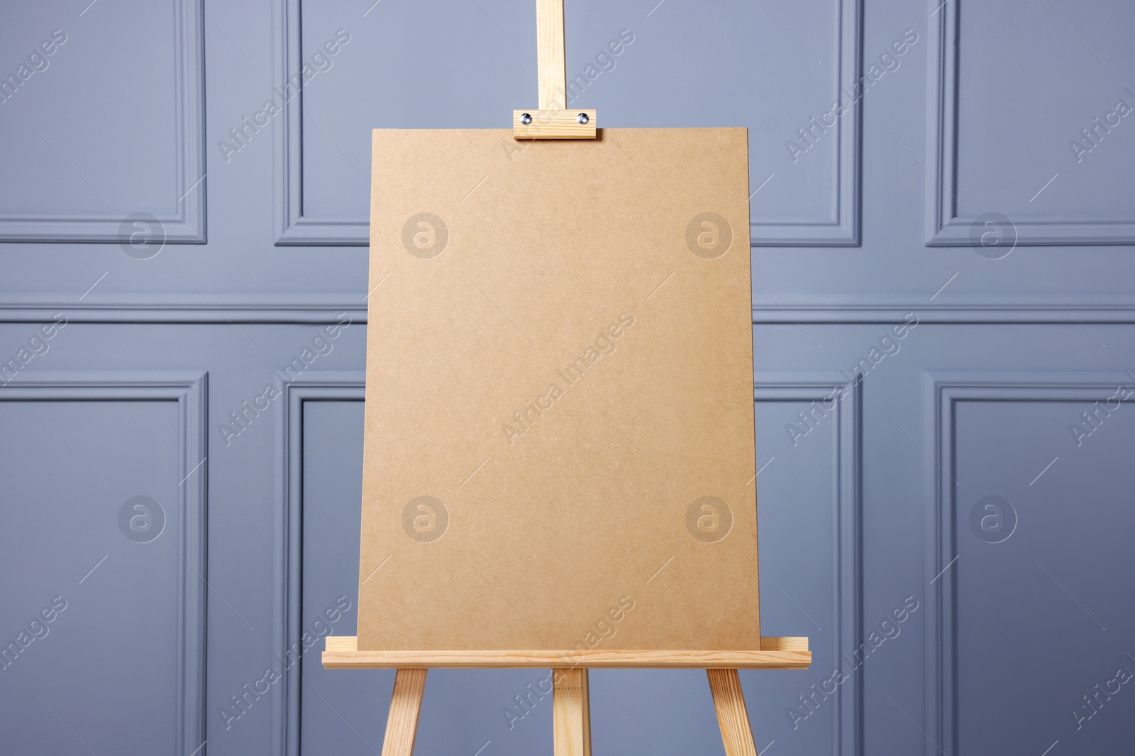 Photo of Wooden easel with blank board near grey wall indoors, closeup