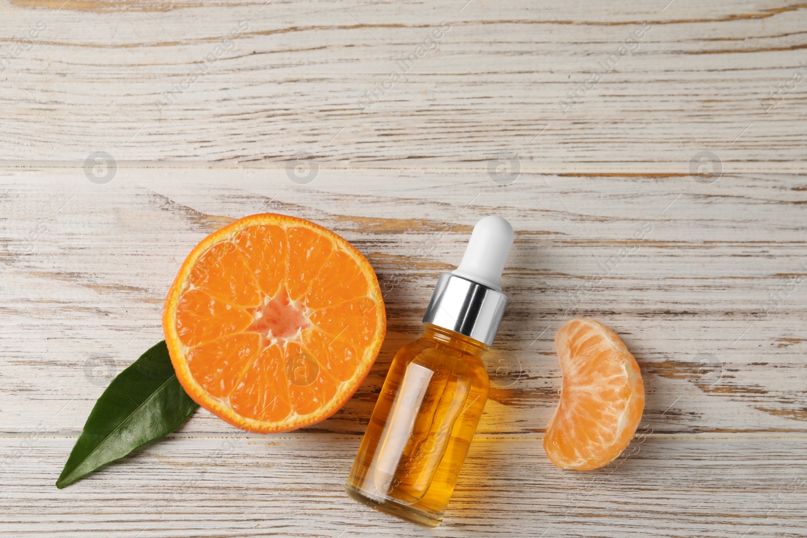 Photo of Bottle of tangerine essential oil and fresh fruit on white wooden table, flat lay