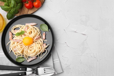 Photo of Plate of tasty pasta Carbonara with egg yolk on white textured table, flat lay. Space for text