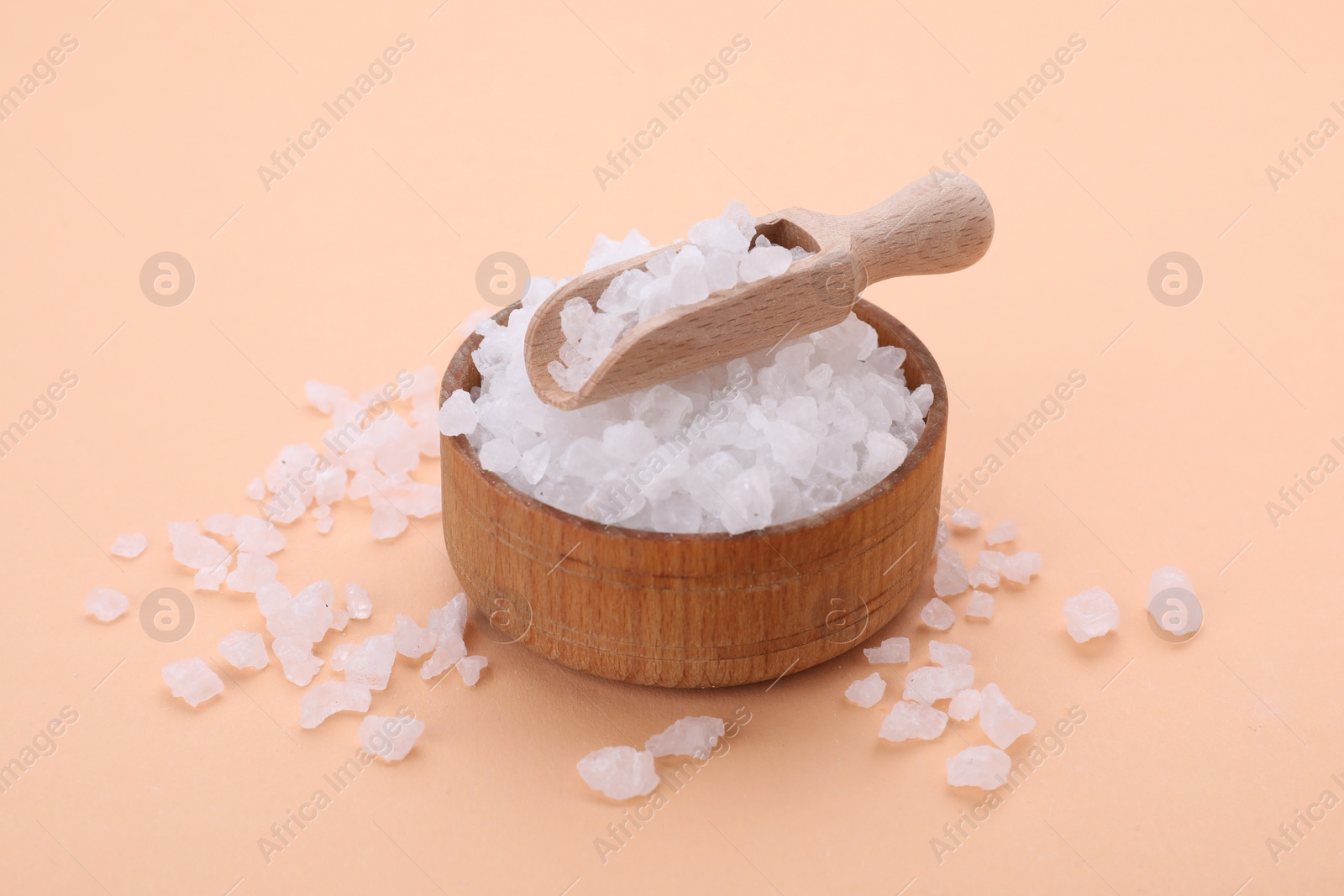 Photo of Bowl and scoop with sea salt on beige background, closeup