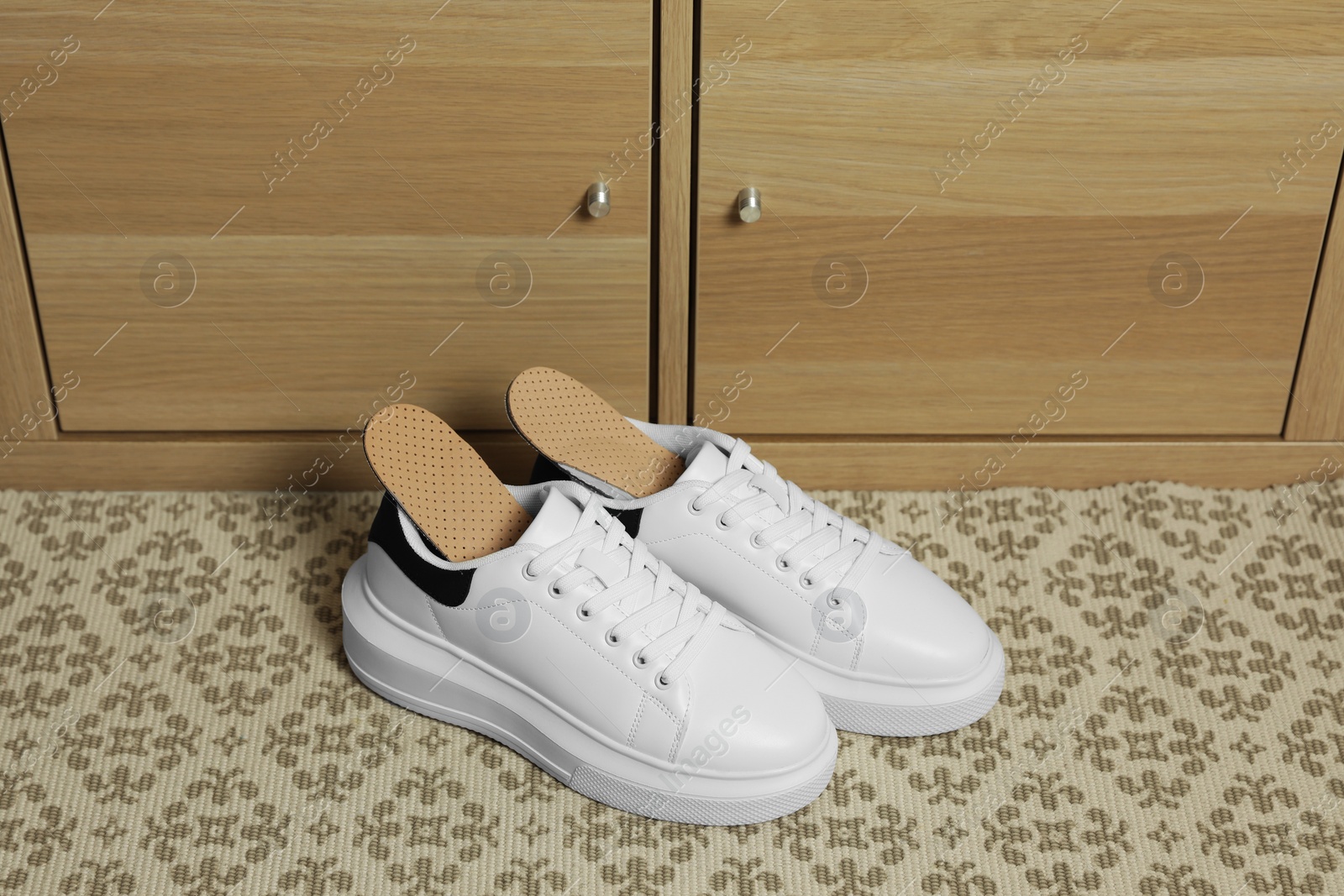 Photo of Orthopedic insoles in shoes on floor near drawer