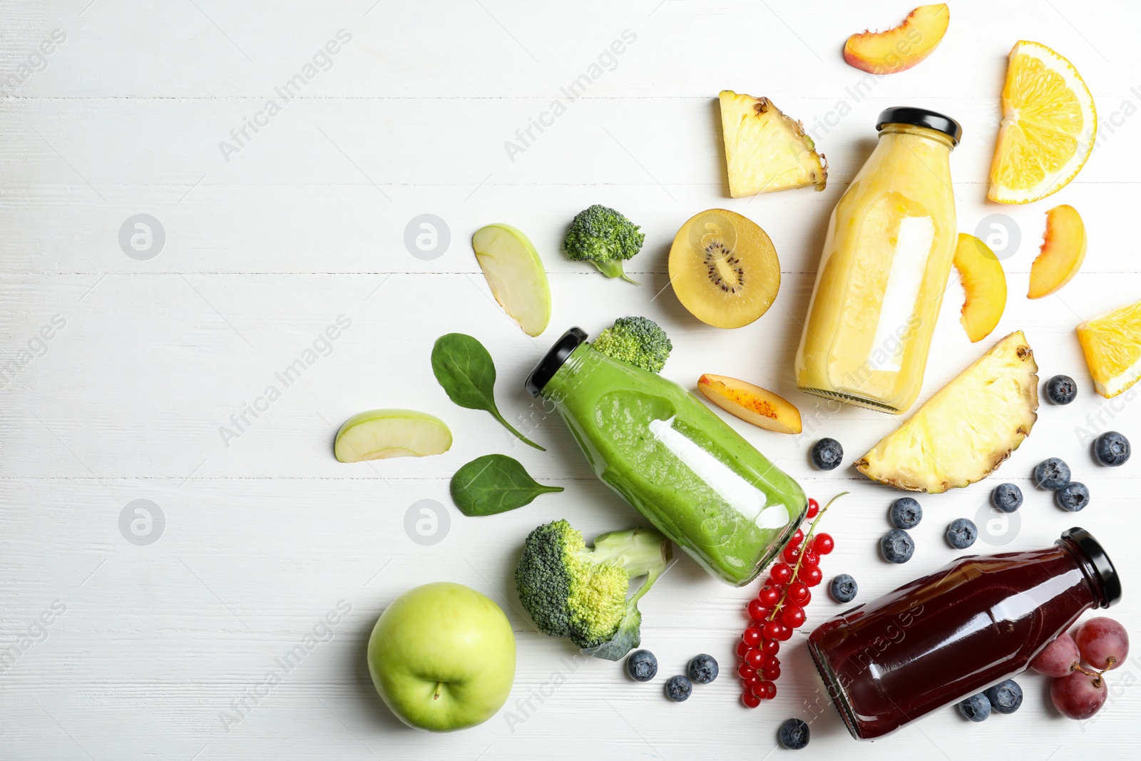 Photo of Bottles of delicious juices and fresh fruits on white wooden table, flat lay. Space for text