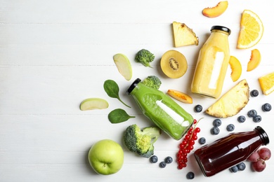 Photo of Bottles of delicious juices and fresh fruits on white wooden table, flat lay. Space for text