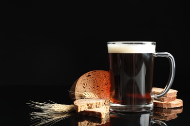 Photo of Delicious kvass, bread and spikes on black background. Space for text