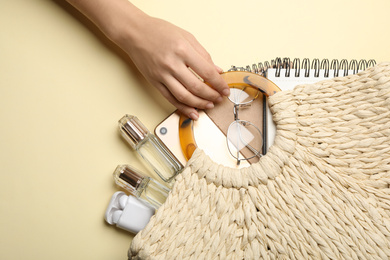 Woman holding stylish bag on light yellow background, top view