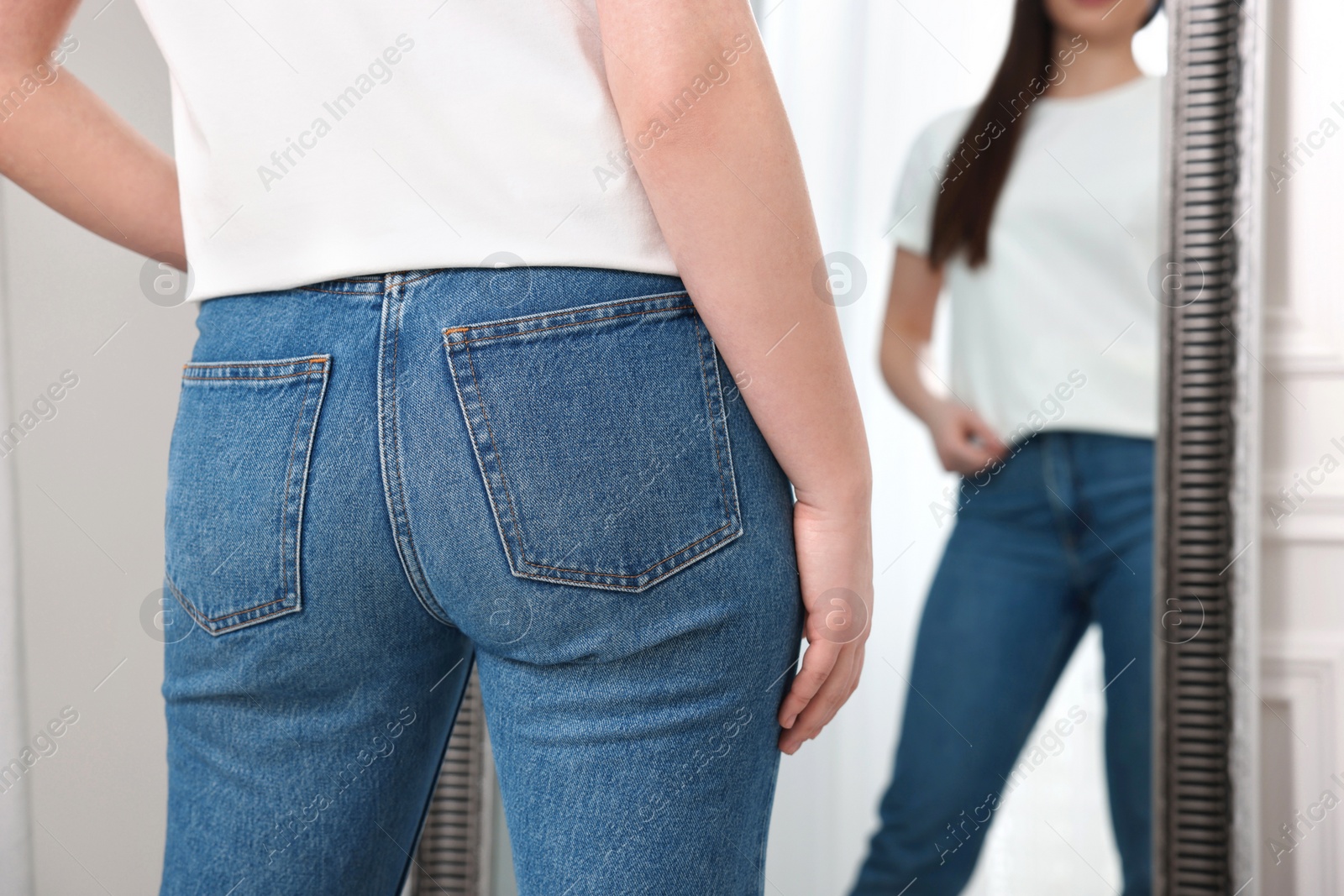 Photo of Woman in stylish jeans near mirror indoors, closeup