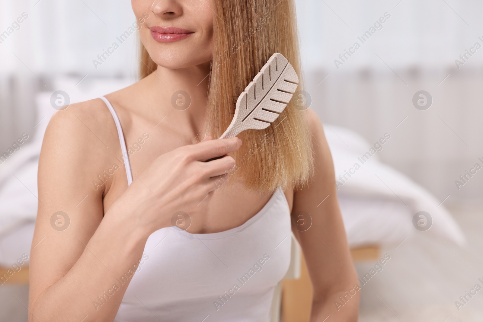 Photo of Woman brushing her hair in room, closeup