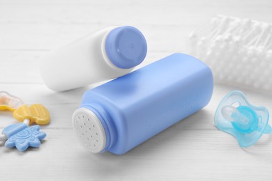 Photo of Baby powder, pacifier and cotton buds on white wooden table, closeup
