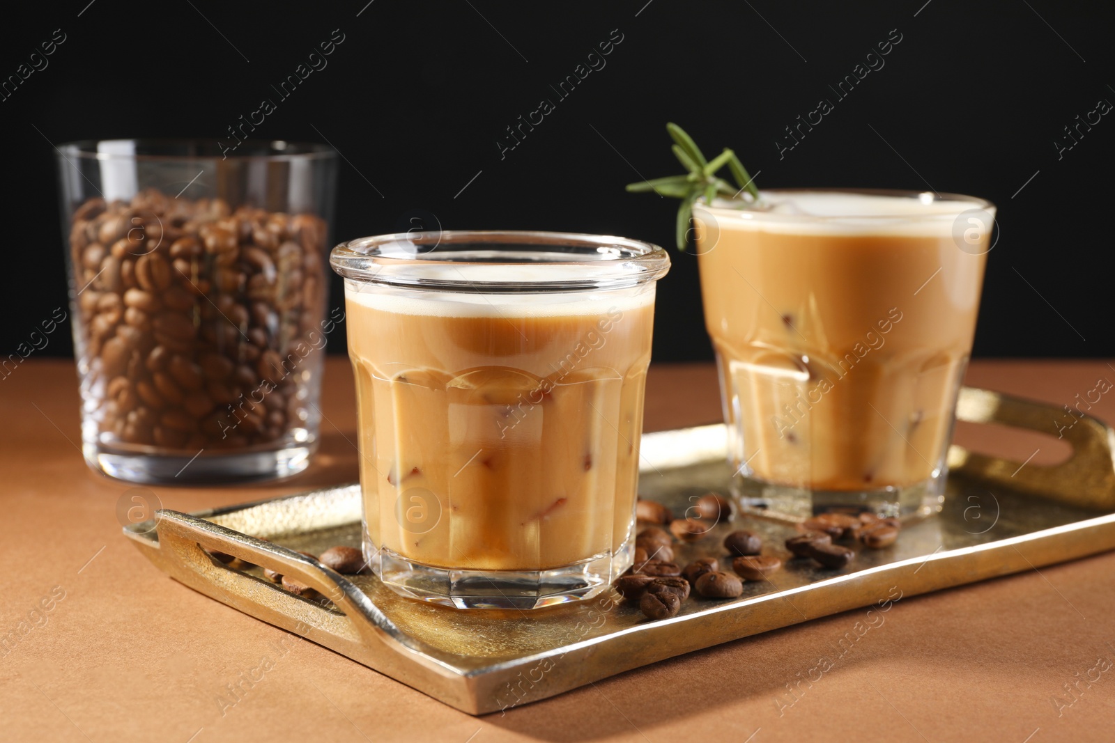 Photo of Refreshing iced coffee with milk in glasses and beans on brown table