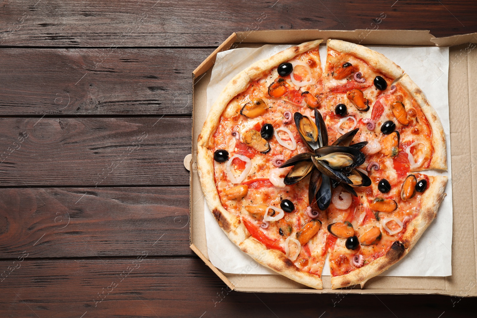 Photo of Tasty pizza with seafood on wooden table, top view. Space for text