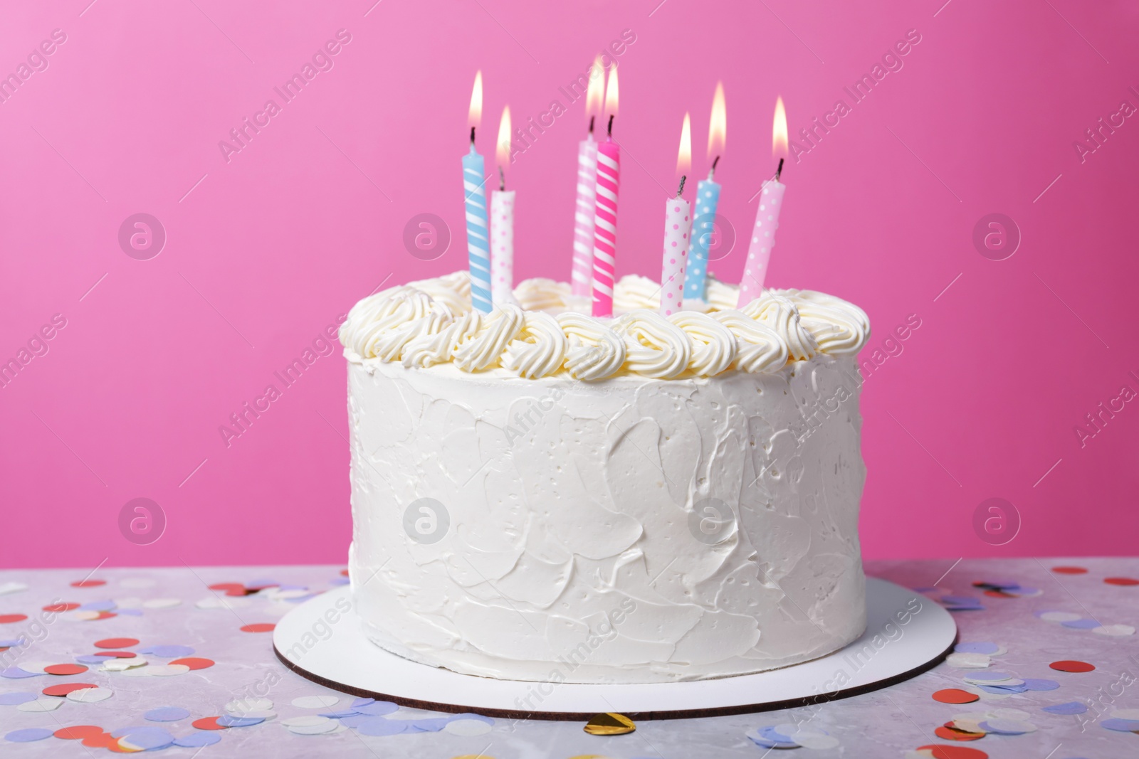 Photo of Delicious cake with cream and burning candles on grey table