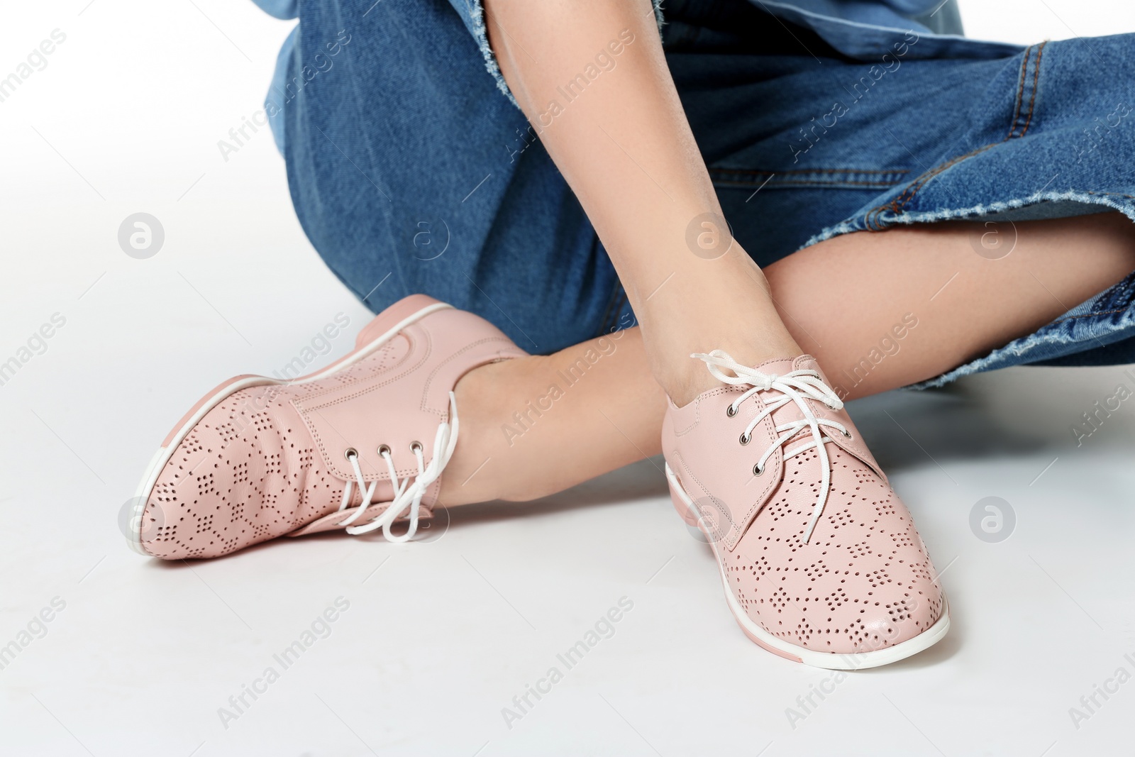 Photo of Woman in stylish shoes sitting on white background, closeup